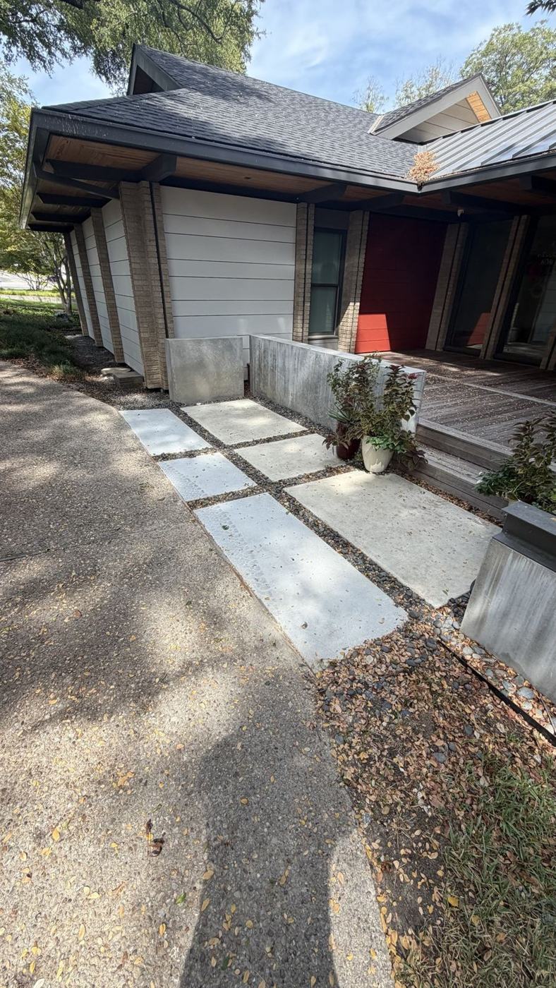 Modern concrete slab walkway with river rock and board-formed walls